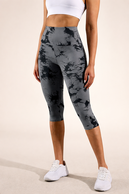 Person wearing gray camouflage leggings with a white top and sneakers on a beige background