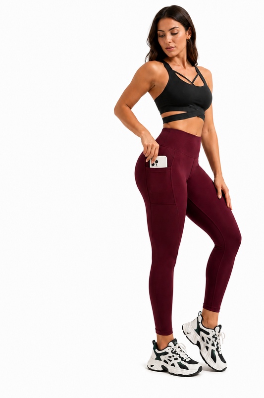 Athletic woman wearing Freedom Flow™ Everyday Pocket Leggings in Burgundy, highlighting the practical side phone pocket, sculpting high-waisted fit and all-day comfort against a clean white studio background.