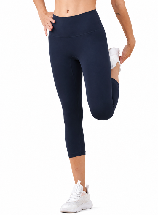 Model wearing Freedom Flow™ Studio Capri Leggings in deep ocean while stretching. High-waisted women's yoga leggings with a supportive, flexible fit by Mind Body & Soles.