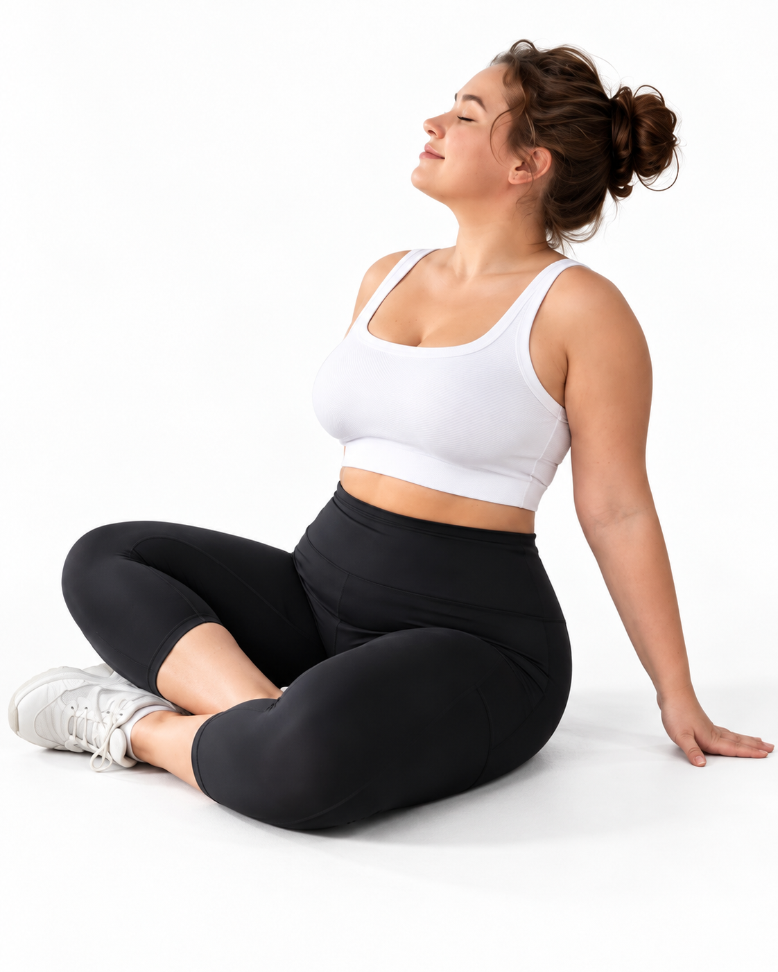 Mind Body and Soles Activewear model wearing black high-waisted capri leggings and a white sports bra, sitting cross-legged