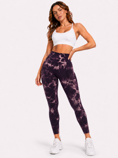 Woman modelling purple and white marble-pattern high-waisted leggings with a white sports bra and white trainers on a plain white background.