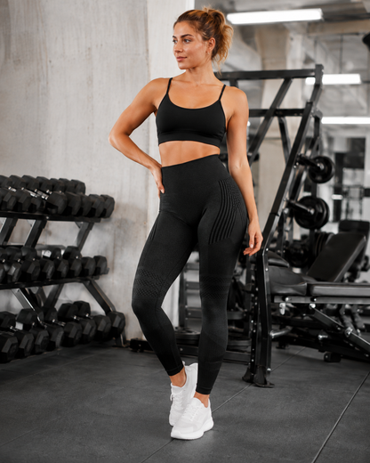 Power Vibe™ Sculpt black women’s seamless high-waisted leggings shown from the front in a modern gym, highlighting the wide ribbed waistband, sculpting contour knit and textured compression panels for strength training and activewear.